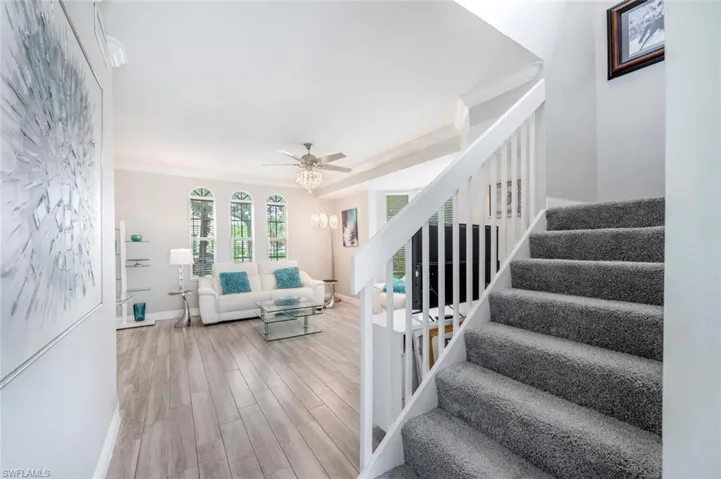 Stairs featuring hardwood / wood-style flooring, crown molding, and ceiling fan