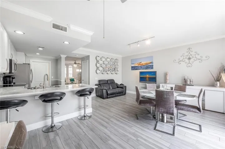 Dining area featuring crown molding, rail lighting, ceiling fan, light hardwood / wood-style floors, and sink