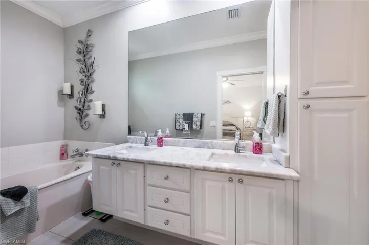 Bathroom featuring a washtub, ceiling fan, crown molding, and double vanity