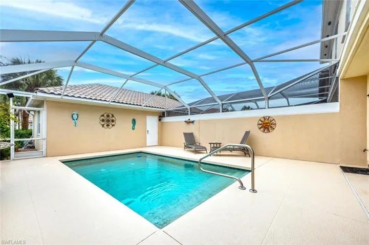 View of swimming pool with glass enclosure and a patio area
