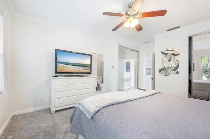Carpeted bedroom featuring connected bathroom, crown molding, a closet, and ceiling fan