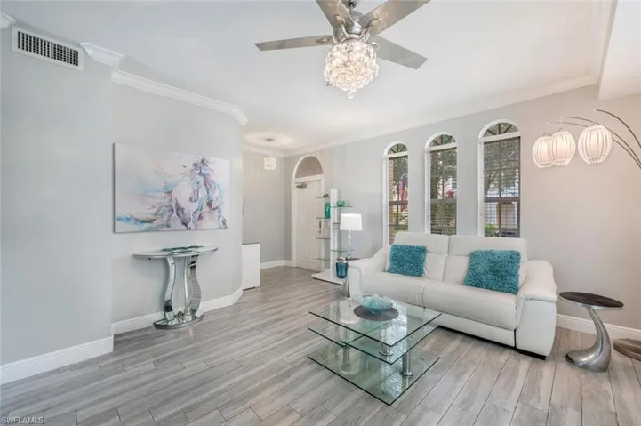 Living room featuring crown molding, light wood-type flooring, and ceiling fan
