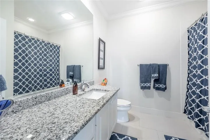 Bathroom featuring tile patterned floors, toilet, vanity, and ornamental molding