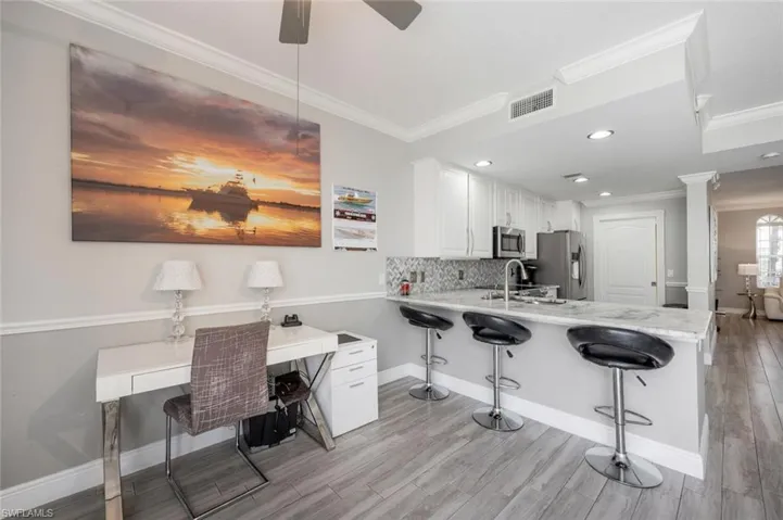 Kitchen with ceiling fan, white cabinets, appliances with stainless steel finishes, kitchen peninsula, and backsplash