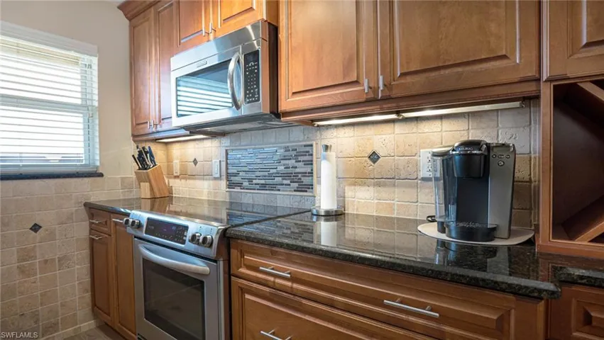 Kitchen with stainless steel appliances, decorative backsplash, a wealth of natural light, and dark stone counters