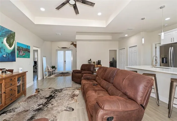 Living room featuring a tray ceiling, french doors, wood tiled floors, and recessed lighting