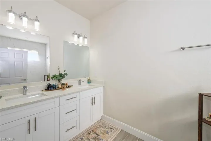 Full bath featuring double vanity and a marble finish shower
