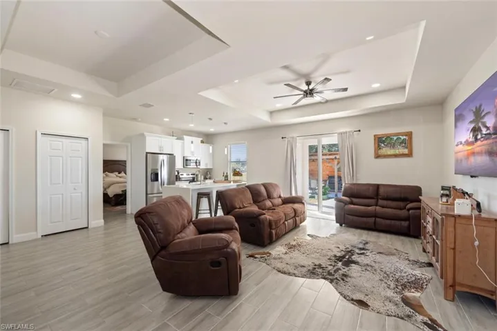 Living room featuring wood tiled floors, a tray ceiling, recessed lighting, and ceiling fan