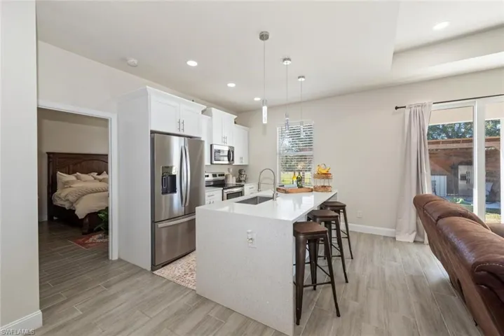 Kitchen featuring stainless steel appliances, hanging light fixtures, wood finish floors, white cabinets, and recessed lighting