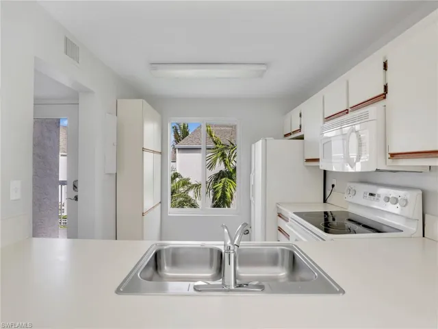 Kitchen with white cabinetry, sink, and white appliances