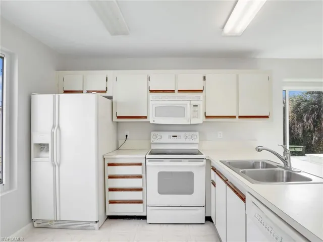 Kitchen with sink, white cabinets, and white appliances
