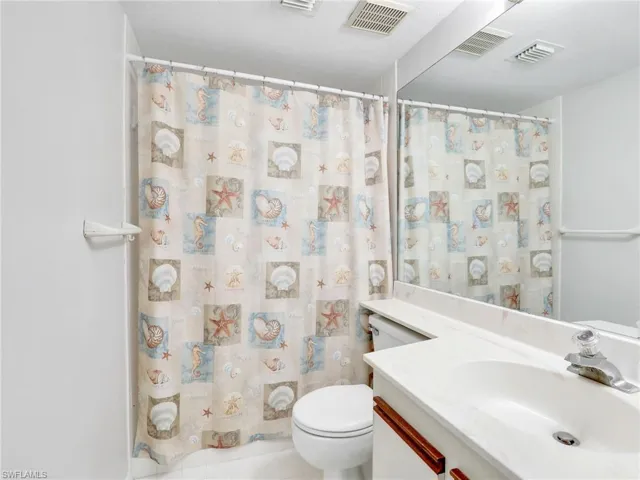 Bathroom with a shower with shower curtain, vanity, and toilet