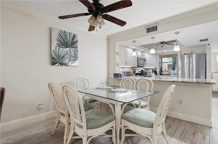 Dining room with crown molding, a ceiling fan, and light wood-style flooring