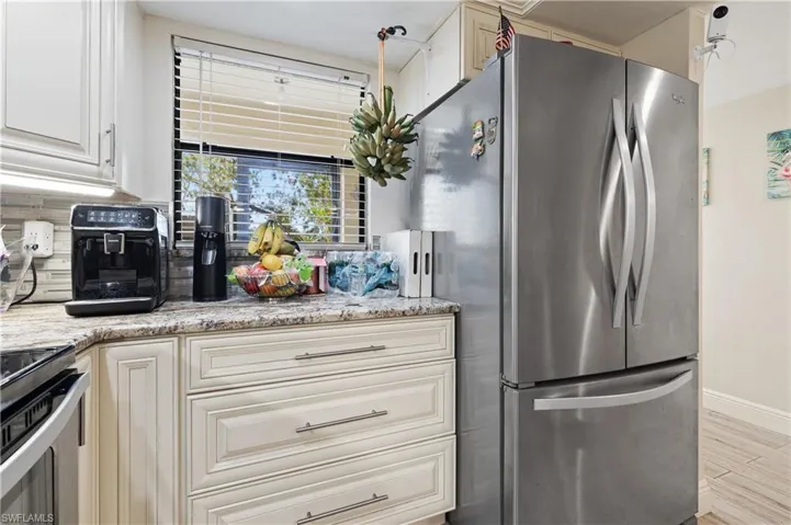 Kitchen featuring stainless steel appliances, light stone counters, light wood finished floors, and white cabinets