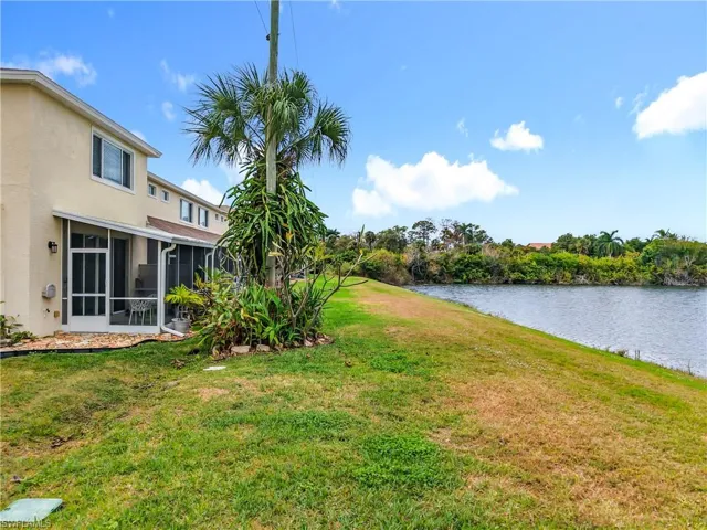 View of grassy yard featuring a sunroom and a water view
