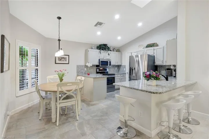 Kitchen featuring white cabinetry, lofted ceiling, appliances with stainless steel finishes, and kitchen peninsula