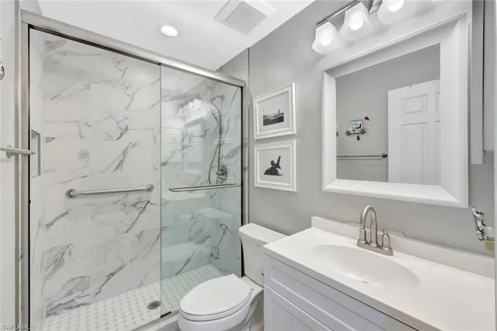 Bathroom with vanity, a shower with shower door, and toilet