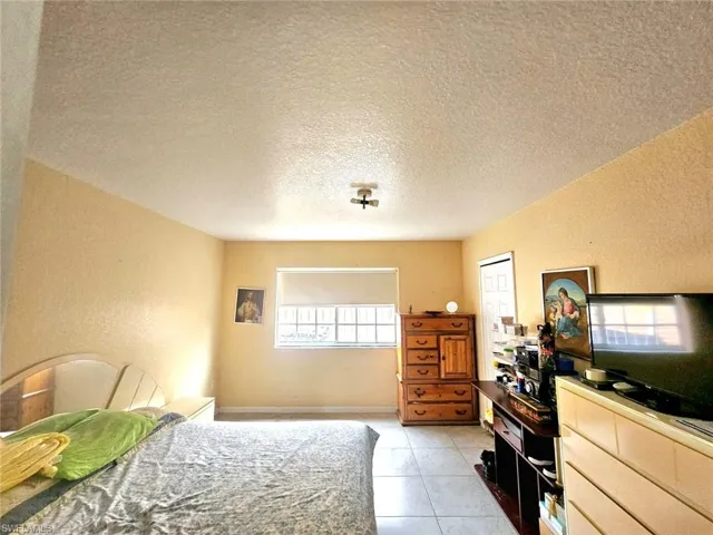 Tiled bedroom featuring a textured ceiling and a closet