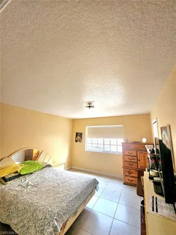 Bedroom with a textured ceiling and light tile patterned floors