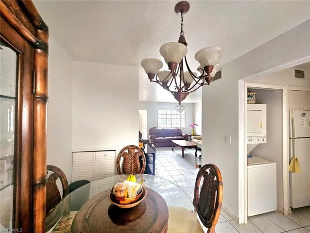 Tiled dining room featuring stacked washer / dryer, a textured ceiling, and an inviting chandelier