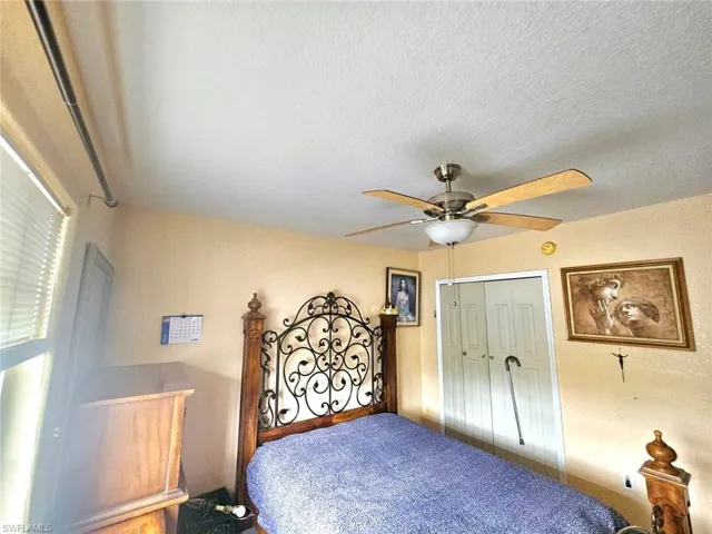 Bedroom with ceiling fan, a textured ceiling, and a closet