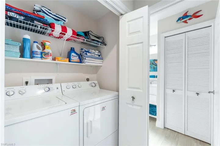 Laundry area with separate washer and dryer and light wood-style floors