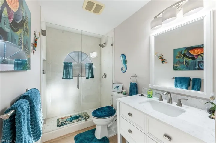 Full bath featuring vanity, a stall shower, and light wood-style flooring