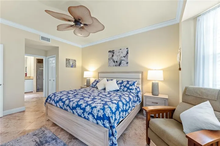 Bedroom with ornamental molding, a closet, a ceiling fan, ensuite bathroom, and multiple windows