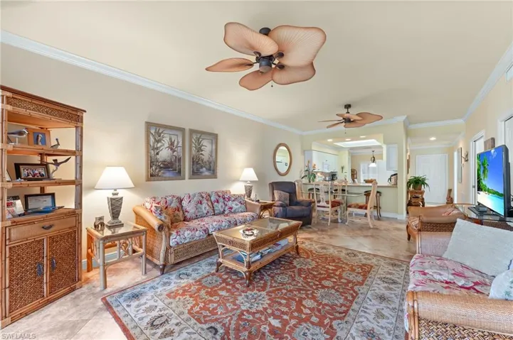 Living area featuring ornamental molding, a ceiling fan, and light tile patterned floors