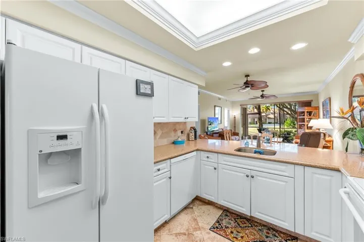 Kitchen with white appliances, open floor plan, recessed lighting, tasteful backsplash, and white cabinetry