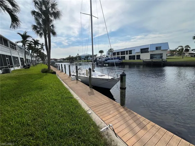 View of dock with a water view and a lawn