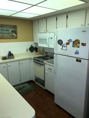 Kitchen featuring backsplash, white appliances, and dark hardwood / wood-style floors