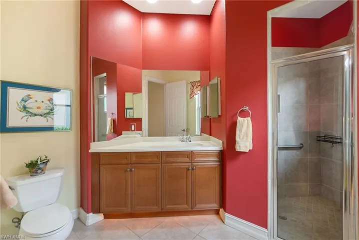 Bathroom featuring tile flooring, vanity, toilet, and a shower with door