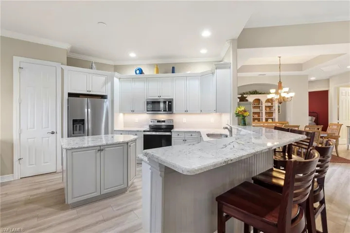 Kitchen featuring light hardwood / wood-style floors, kitchen peninsula, pendant lighting, a breakfast bar area, and appliances with stainless steel finishes