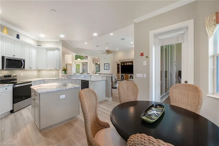 Kitchen with light stone countertops, kitchen peninsula, a kitchen island, white cabinetry, and appliances with stainless steel finishes
