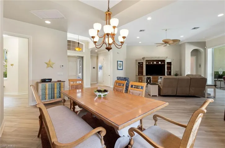 Dining area with light hardwood / wood-style flooring and ceiling fan with notable chandelier