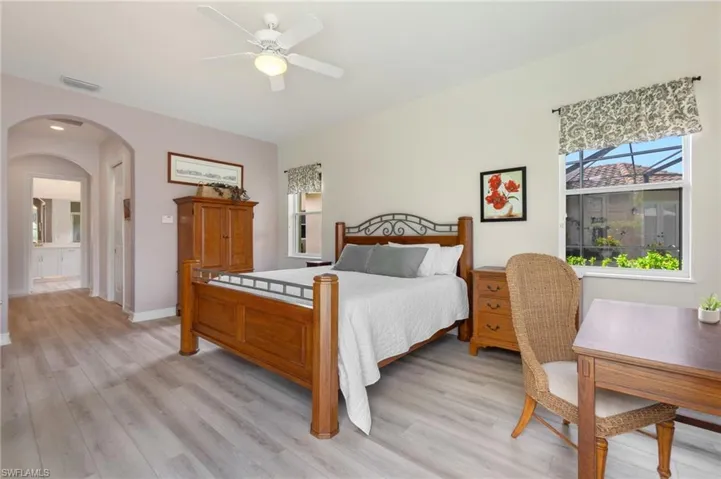 Bedroom with ceiling fan, light hardwood / wood-style floors, and connected bathroom