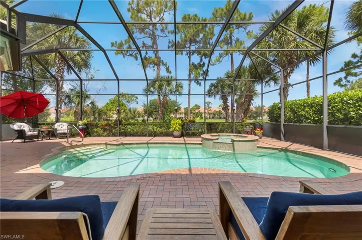 View of pool featuring glass enclosure, an in ground hot tub, and a patio area