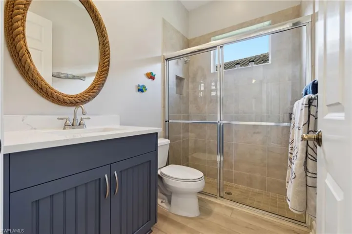 Bathroom featuring an enclosed shower, toilet, and vanity