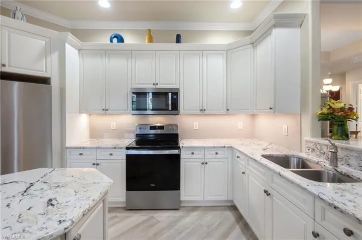 Kitchen with white cabinets, appliances with stainless steel finishes, sink, and tasteful backsplash
