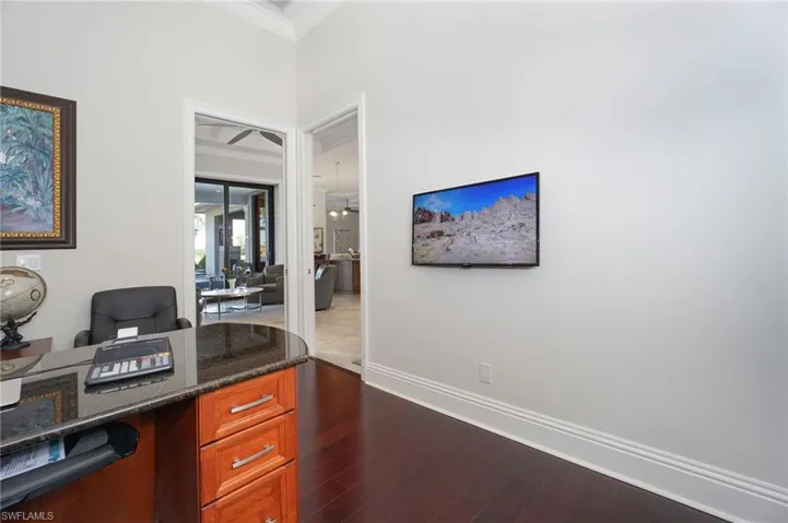 Home office with dark wood-type flooring and crown molding