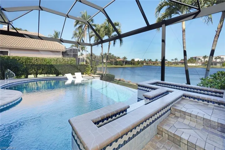 View of pool with glass enclosure and a water view