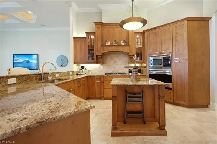 Kitchen featuring pendant lighting, sink, light stone countertops, appliances with stainless steel finishes, and kitchen peninsula
