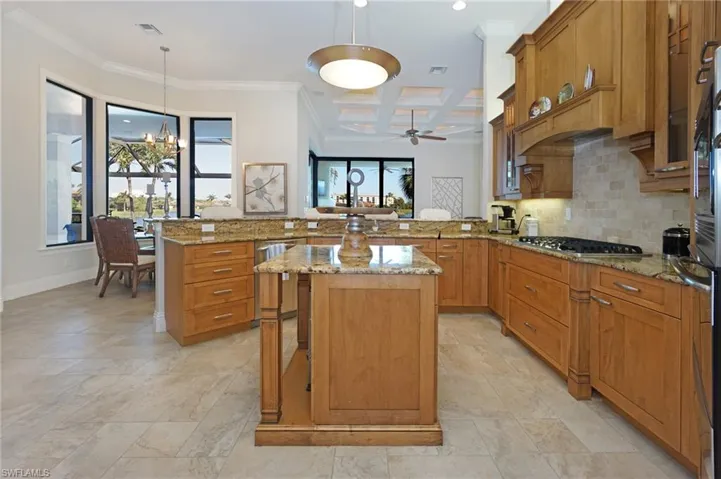 Kitchen with a center island, coffered ceiling, decorative light fixtures, kitchen peninsula, and stainless steel appliances