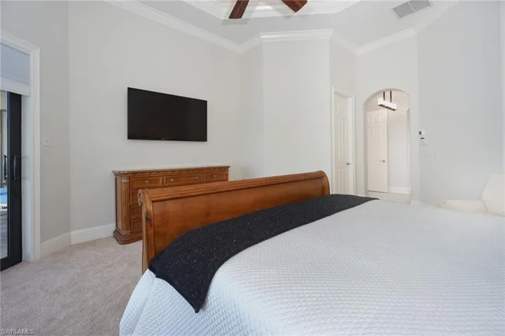 Carpeted bedroom with ceiling fan and crown molding