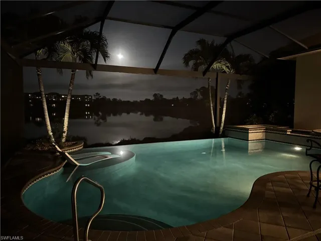 Pool at twilight featuring an in ground hot tub and a water view