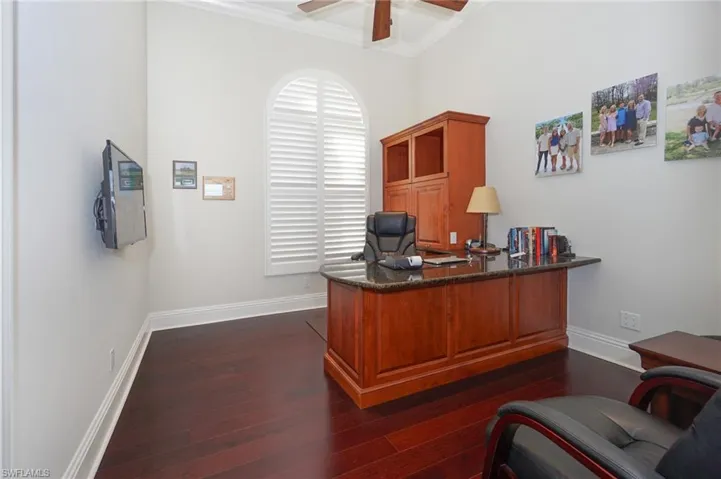 Office space with ceiling fan, dark wood-type flooring, and ornamental molding