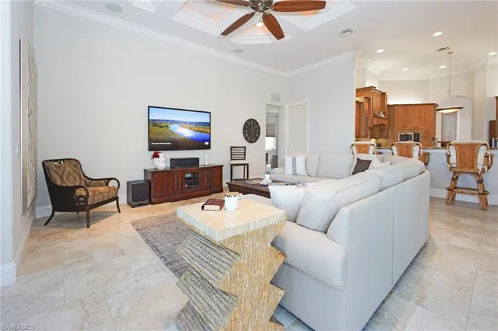 Living room featuring crown molding, ceiling fan, a high ceiling, and coffered ceiling