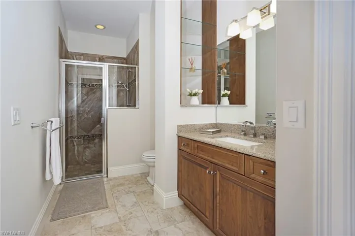 Bathroom featuring vanity, toilet, and an enclosed shower