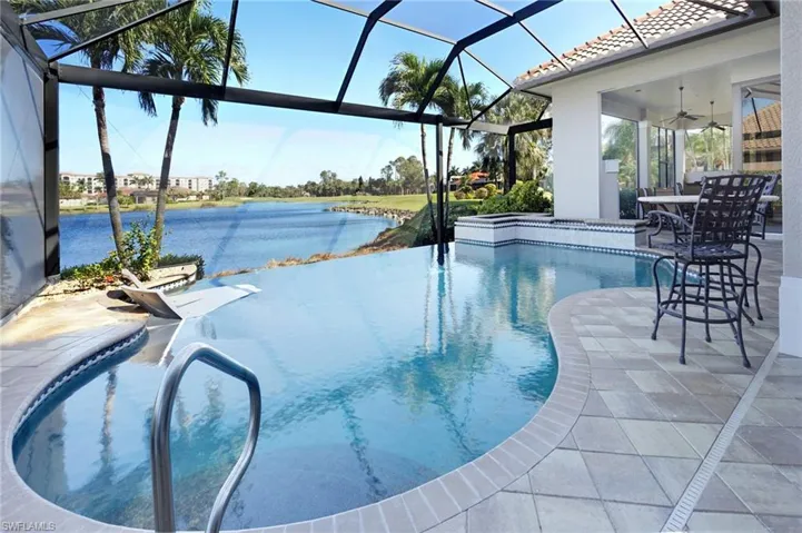 View of pool with ceiling fan, a water view, a patio, and glass enclosure